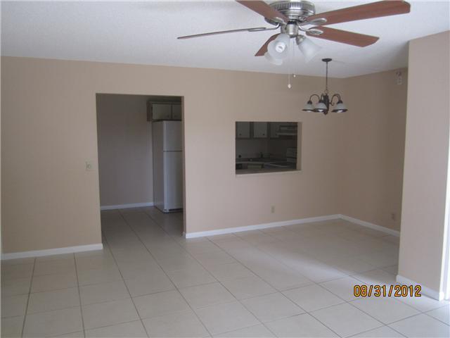 empty room featuring light tile patterned floors and ceiling fan with notable chandelier