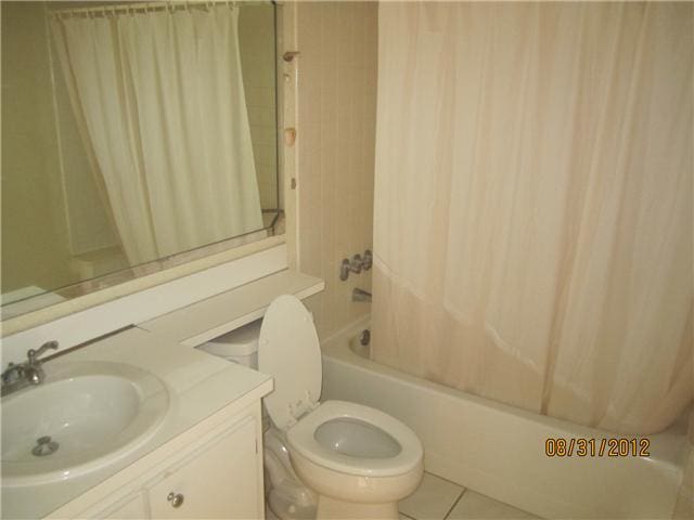 full bathroom featuring tile patterned flooring, shower / bath combination with curtain, toilet, and sink