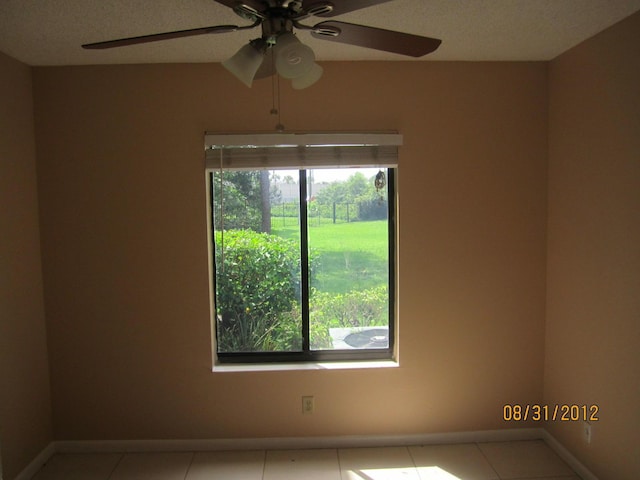 spare room featuring ceiling fan, light tile patterned flooring, and a textured ceiling