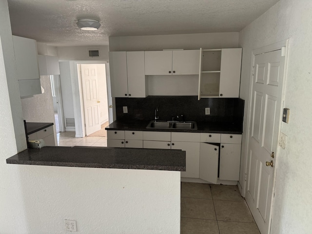 kitchen with white cabinets, decorative backsplash, kitchen peninsula, and sink