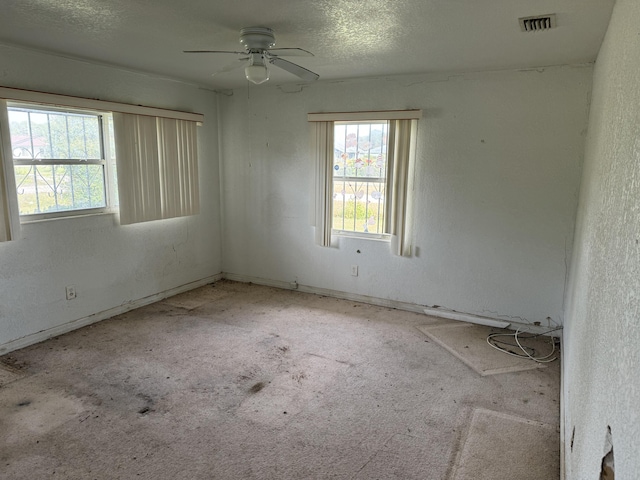 empty room featuring a textured ceiling, light colored carpet, and ceiling fan