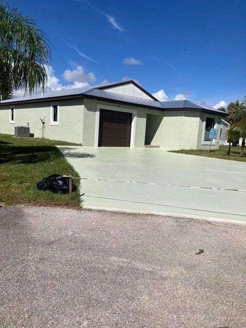 view of front of home featuring central AC unit, a garage, and a front lawn