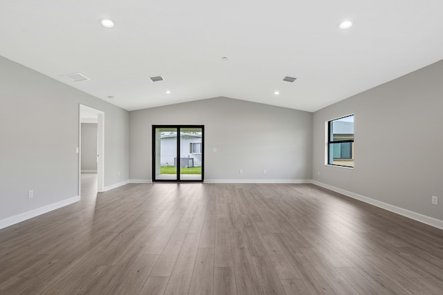 unfurnished room featuring lofted ceiling, plenty of natural light, recessed lighting, and wood finished floors