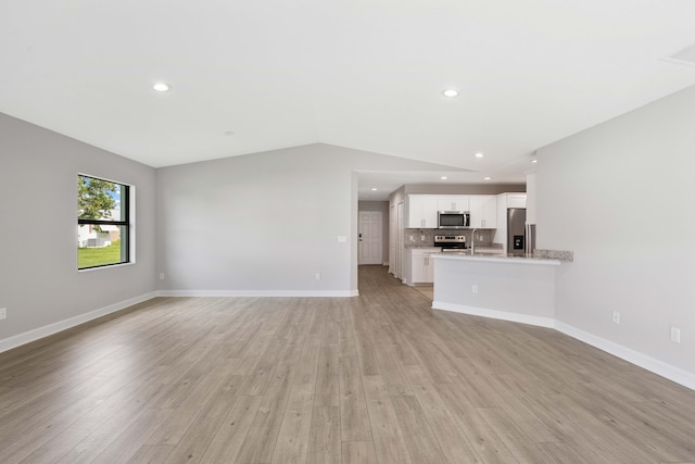 unfurnished living room featuring light wood-type flooring, baseboards, and recessed lighting