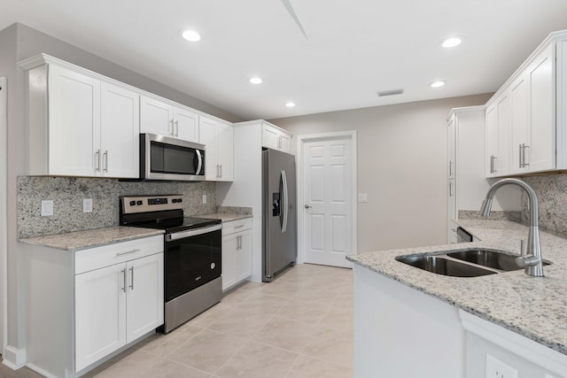 kitchen with light stone counters, stainless steel appliances, visible vents, white cabinetry, and a sink