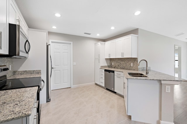 kitchen with visible vents, white cabinets, a peninsula, stainless steel appliances, and a sink