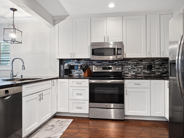 kitchen featuring sink, white cabinets, hanging light fixtures, and appliances with stainless steel finishes