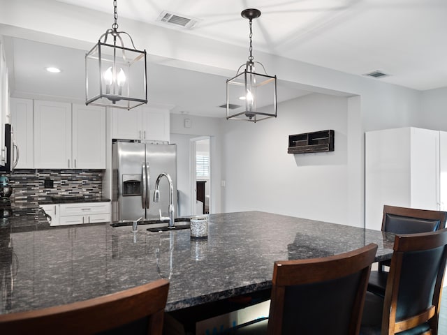 kitchen featuring a kitchen breakfast bar, white cabinetry, appliances with stainless steel finishes, and pendant lighting