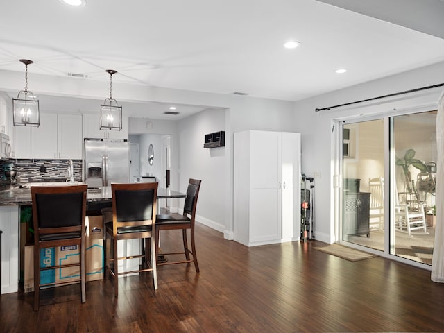 kitchen with backsplash, white cabinets, hanging light fixtures, dark hardwood / wood-style floors, and appliances with stainless steel finishes