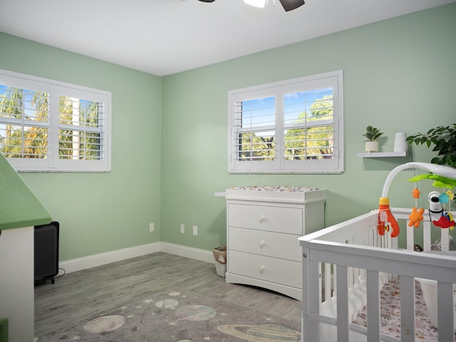 bedroom featuring ceiling fan, a crib, and light hardwood / wood-style flooring