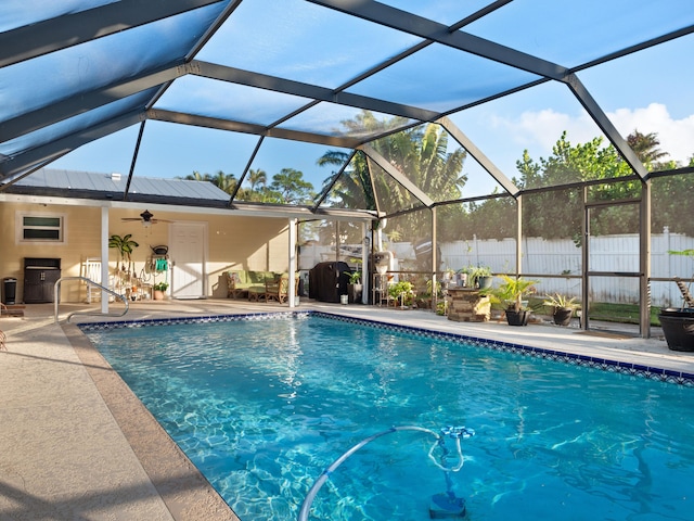 view of swimming pool featuring glass enclosure, ceiling fan, and a patio