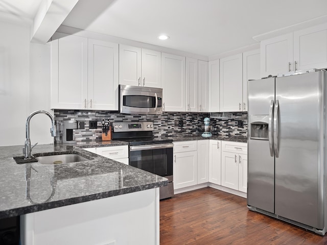 kitchen featuring dark wood-style flooring, a sink, white cabinets, appliances with stainless steel finishes, and dark stone counters