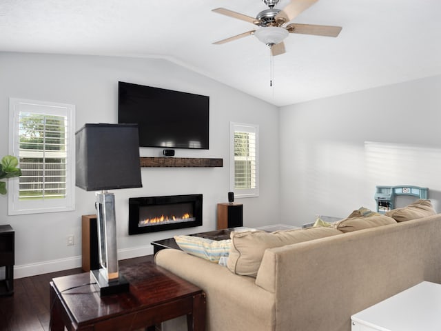 living room with a wealth of natural light, ceiling fan, dark wood-type flooring, and vaulted ceiling