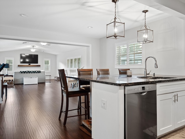 kitchen with dishwasher, a kitchen breakfast bar, sink, dark stone countertops, and white cabinetry