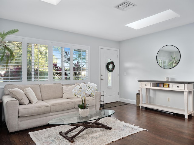 living room with a skylight and dark wood-type flooring