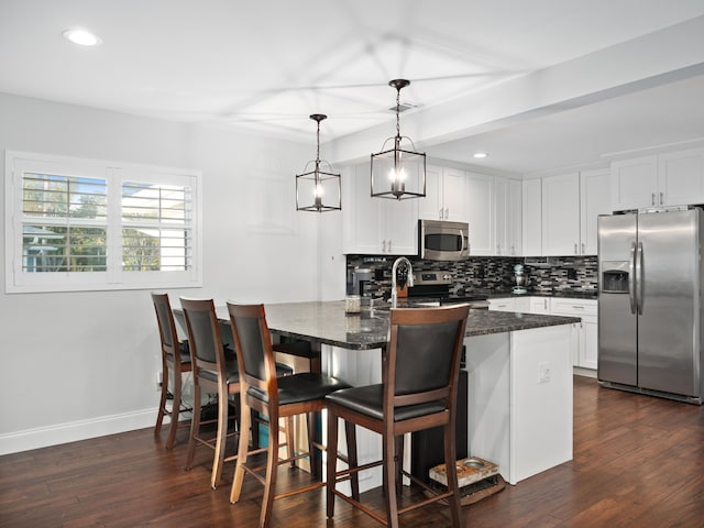 kitchen with white cabinets, pendant lighting, a breakfast bar, and stainless steel appliances