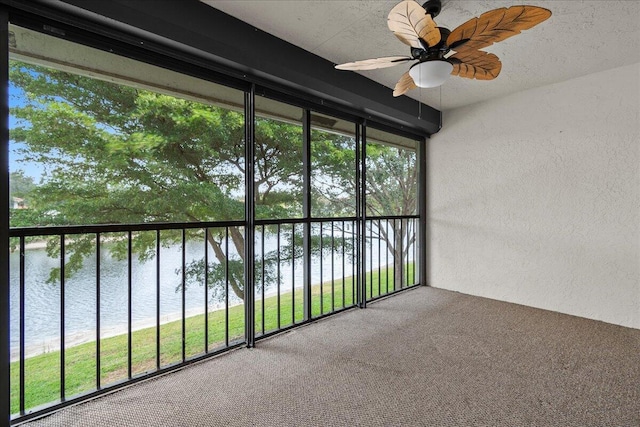 unfurnished sunroom featuring ceiling fan, a water view, and a wealth of natural light