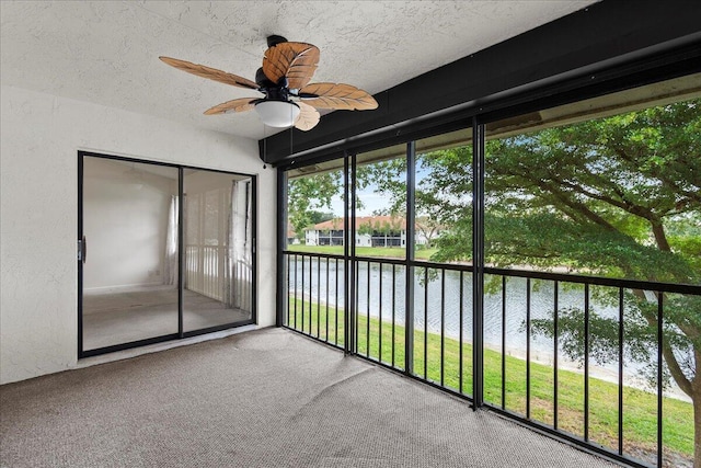 unfurnished sunroom with ceiling fan and a water view