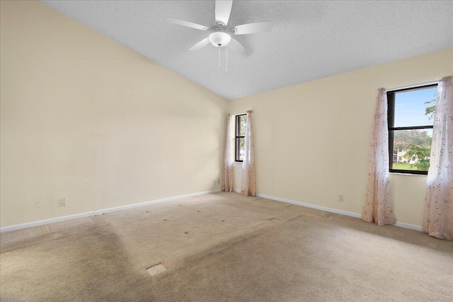 carpeted spare room featuring lofted ceiling, a textured ceiling, ceiling fan, and a wealth of natural light