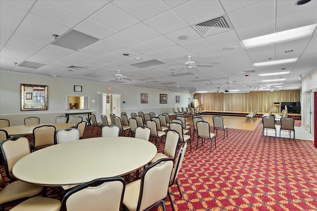 dining space with ceiling fan, a paneled ceiling, and carpet flooring