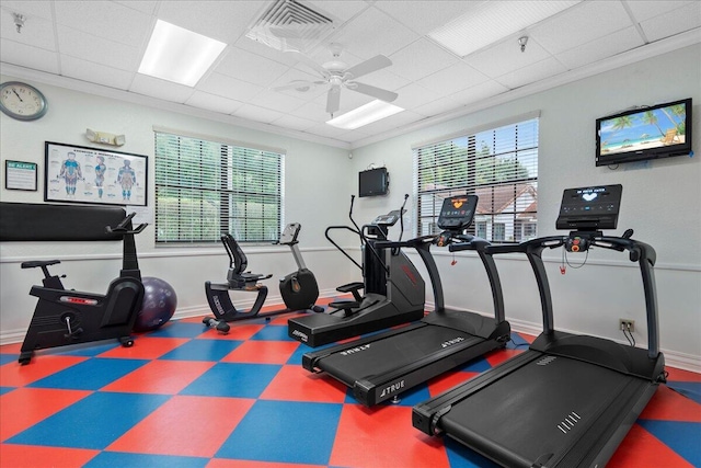 gym featuring a drop ceiling, ceiling fan, and ornamental molding