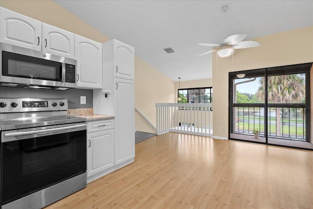 kitchen featuring vaulted ceiling, light wood-type flooring, white cabinets, appliances with stainless steel finishes, and ceiling fan