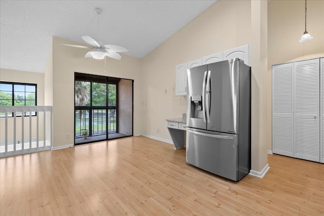 kitchen with white cabinets, ceiling fan, light hardwood / wood-style floors, hanging light fixtures, and stainless steel fridge