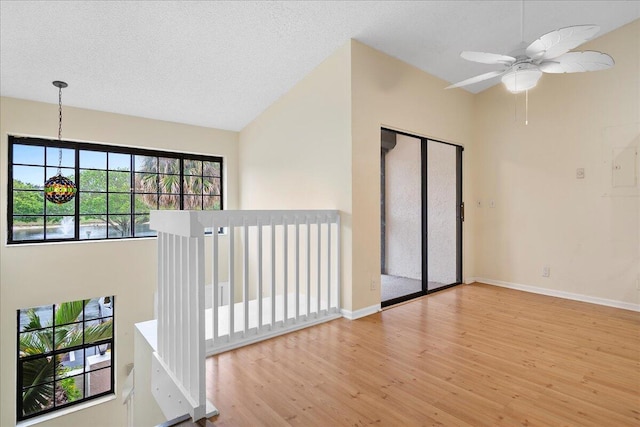 spare room featuring lofted ceiling, a textured ceiling, ceiling fan, and light hardwood / wood-style floors