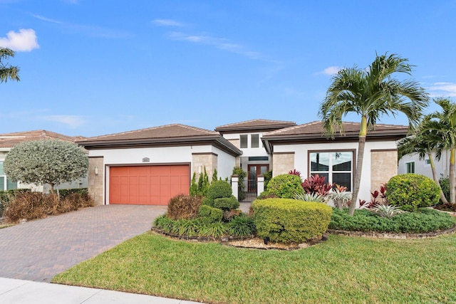 view of front of home with a front lawn, decorative driveway, an attached garage, and stucco siding