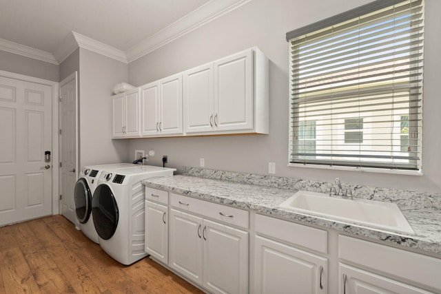 laundry room with cabinets, crown molding, sink, light wood-type flooring, and separate washer and dryer