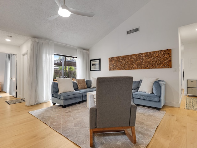 living room with ceiling fan, light hardwood / wood-style flooring, and a textured ceiling