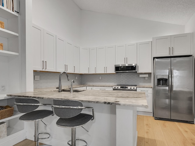 kitchen featuring decorative backsplash, kitchen peninsula, sink, and appliances with stainless steel finishes