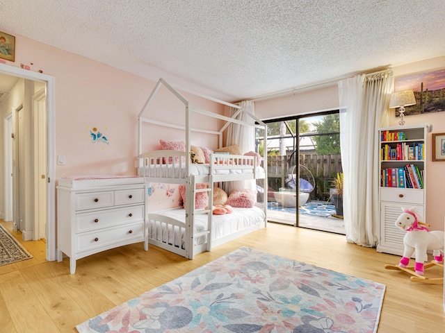 bedroom with light hardwood / wood-style floors, access to exterior, and a textured ceiling