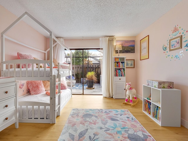 bedroom featuring light hardwood / wood-style floors, access to exterior, and a textured ceiling