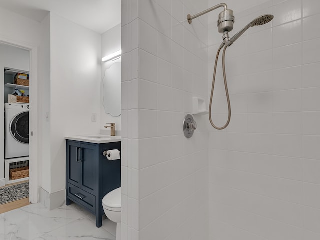 bathroom featuring toilet, washer / dryer, vanity, and a tile shower