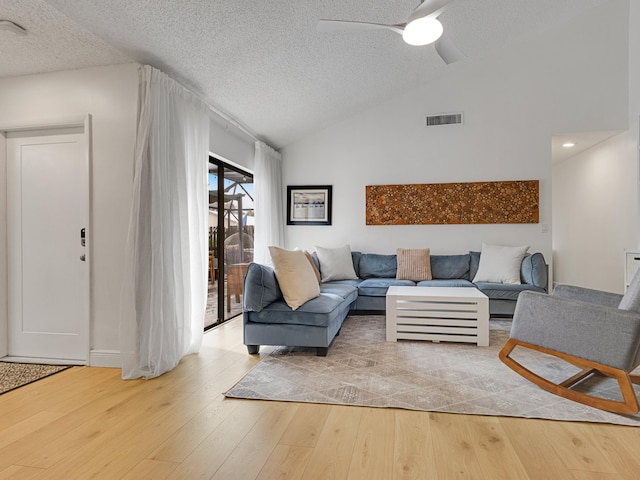 living room featuring a textured ceiling, light hardwood / wood-style flooring, ceiling fan, and vaulted ceiling