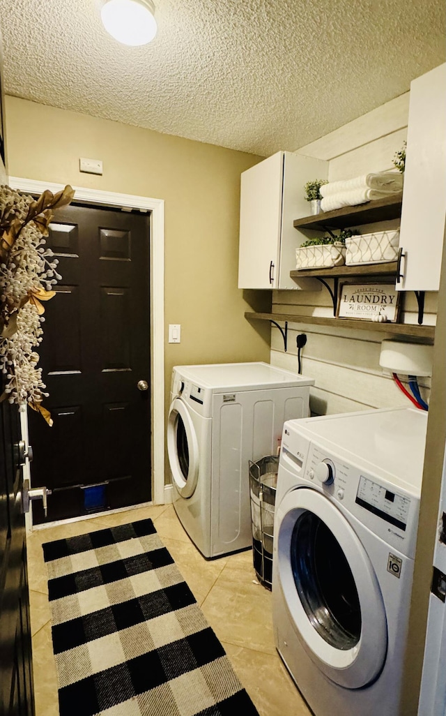 laundry room with a textured ceiling, cabinets, washing machine and clothes dryer, and light tile patterned flooring