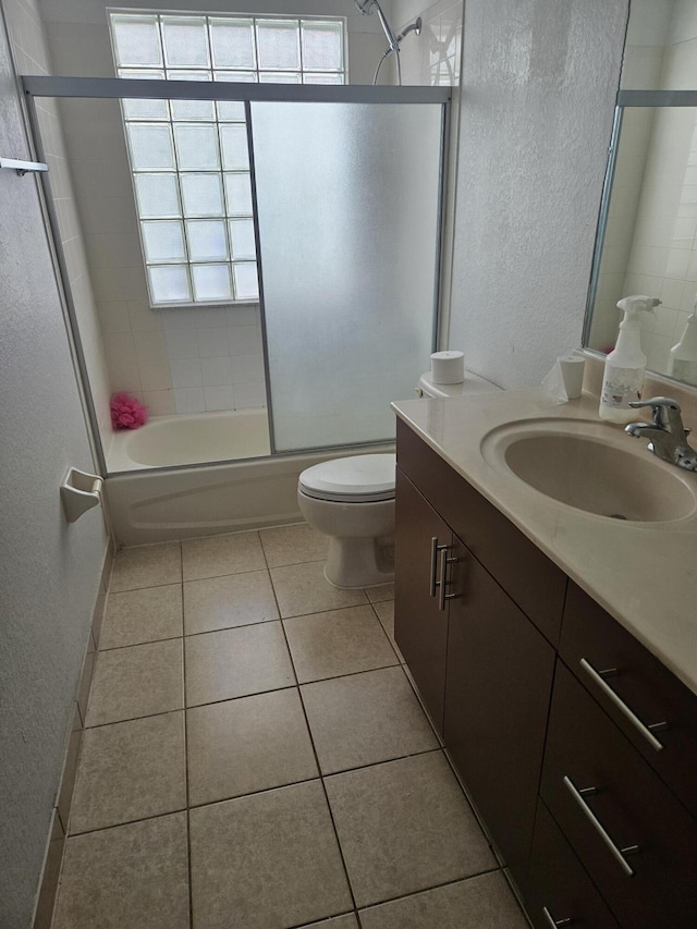 full bathroom with toilet, vanity, tile patterned floors, and enclosed tub / shower combo