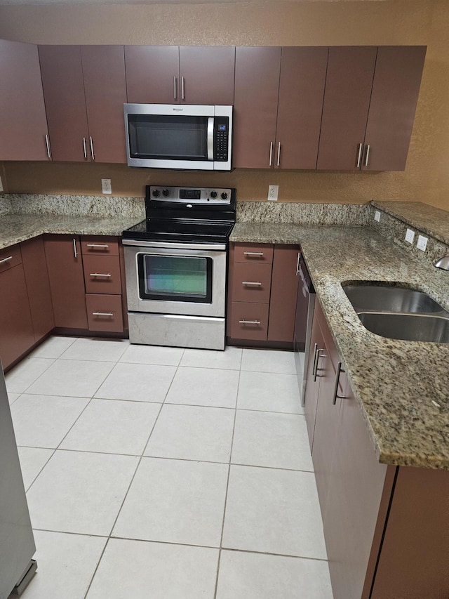 kitchen featuring stone countertops, light tile patterned flooring, sink, and stainless steel appliances