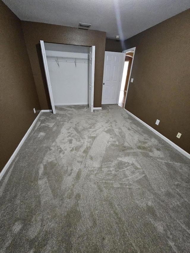 unfurnished bedroom with carpet, a textured ceiling, and a closet