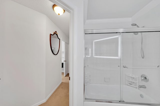 bathroom featuring a textured ceiling, ornamental molding, and enclosed tub / shower combo