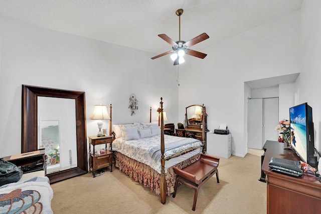 bedroom with ceiling fan, a closet, light colored carpet, and a high ceiling