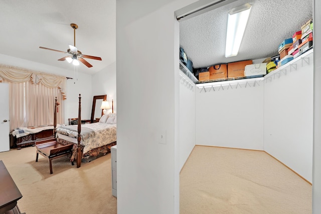 carpeted bedroom featuring ceiling fan and a textured ceiling