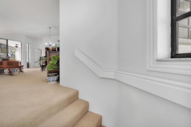 stairway featuring ceiling fan with notable chandelier