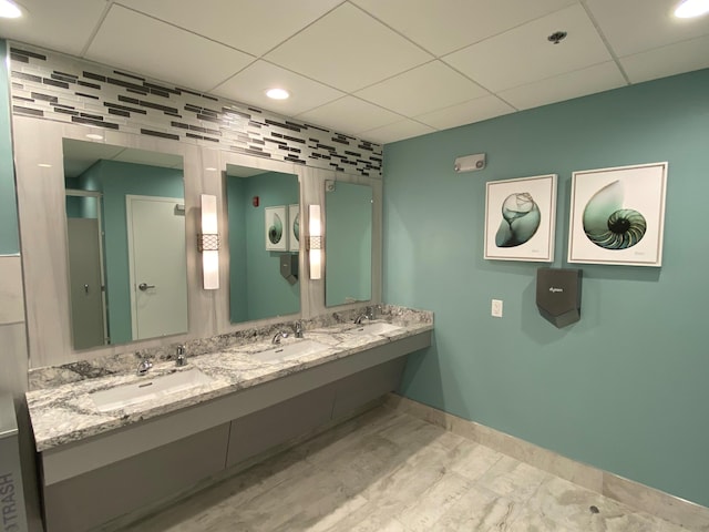 bathroom with decorative backsplash, vanity, and a drop ceiling