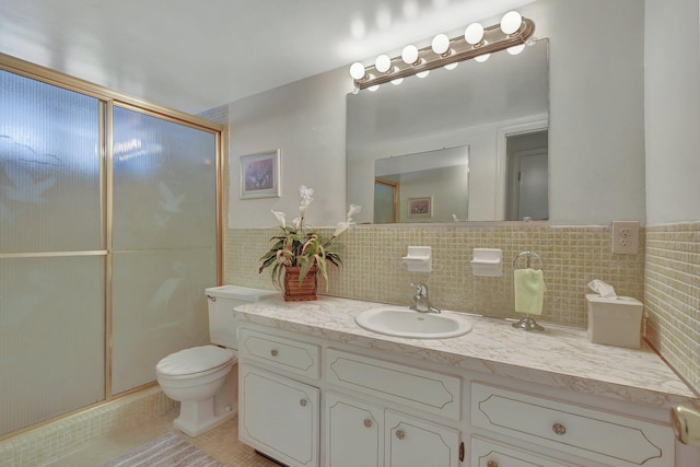 bathroom with vanity, tile patterned floors, toilet, tile walls, and a shower with shower door