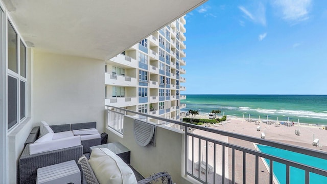 balcony featuring an outdoor hangout area, a water view, and a beach view