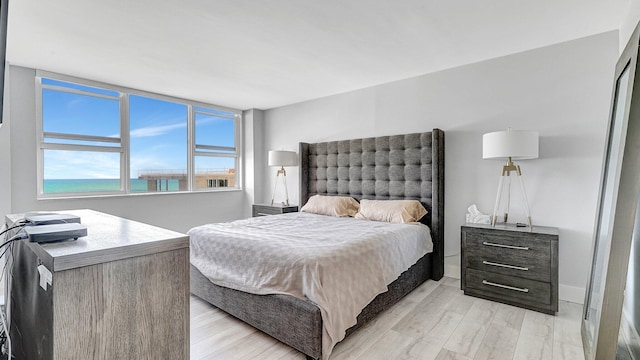 bedroom featuring light wood-type flooring and a water view