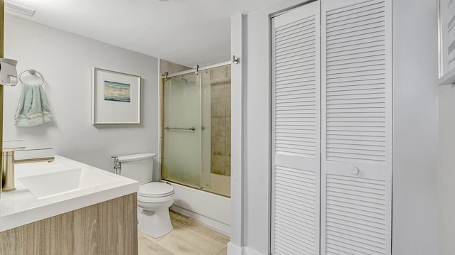 full bathroom featuring hardwood / wood-style flooring, vanity, bath / shower combo with glass door, and toilet