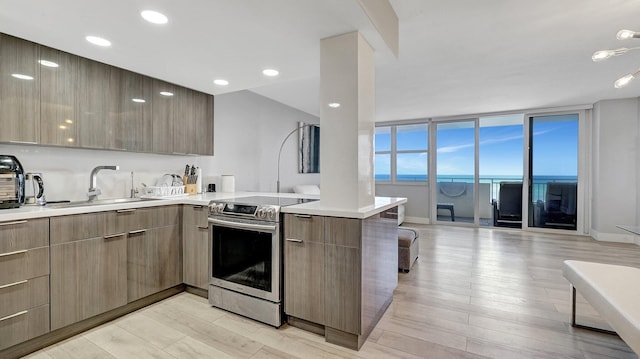 kitchen featuring kitchen peninsula, light wood-type flooring, sink, a water view, and stainless steel electric range